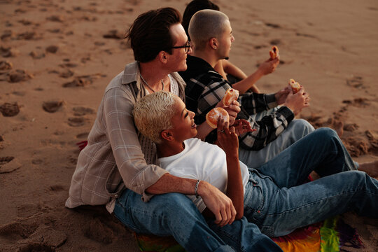 Friends eating donuts and enjoying sunset at the beach
