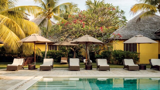 Sunny Poolside Resort Courtyard With Lounge Chairs, Umbrellas, and Palm Trees - Powered by Adobe