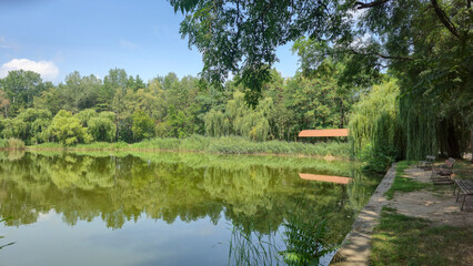 Summer river landscape with green trees, reflections and blue sky. Tourism