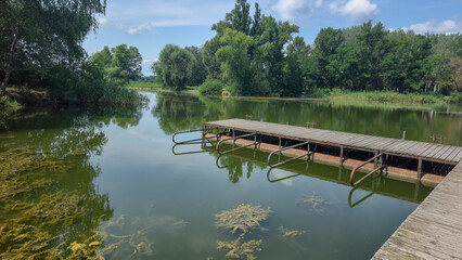 Summer river landscape with green trees, reflections and blue sky. Tourism
