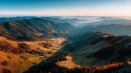 Fototapeta premium Expansive panorama of golden hills and misty mountain ridges under morning light. A majestic and peaceful autumn landscape with forested slopes and natural texture.