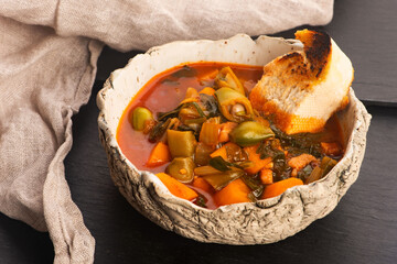 Croatian Potato and Fava Bean Soup with Tomatoes, Celery and Toasted Baguette on Handmade Ceramic Plate