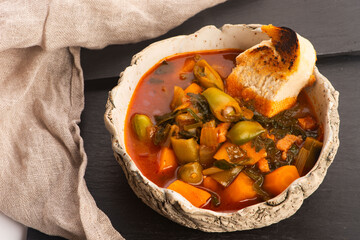 Croatian Potato and Fava Bean Soup with Tomatoes, Celery and Toasted Baguette on Handmade Ceramic Plate