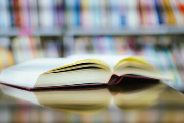 Open book with books piled up on the table in the library. Basic education concept.