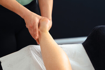 Close-up view of a massage therapist performing a leg massage on a client during a spa session,...