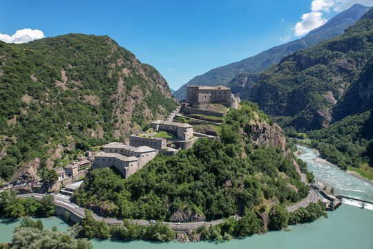Aerial view of the imposing Forte di Bard perched atop a craggy peak, a stone sentinel overlooking the winding Dora Baltea river, Bard, Aosta Valley, Italy.