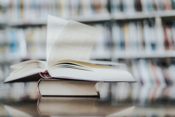 Open book with books piled up on the table in the library. Basic education concept.