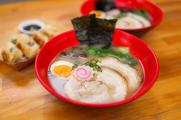 Top-down view of Japanese tonkotsu ramen featuring chashu pork, soft-boiled egg, seaweed, and vegetables in rich broth.
