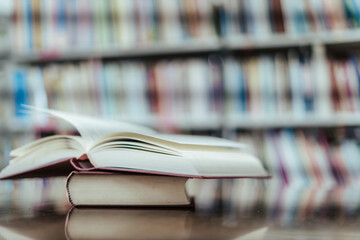Open book with books piled up on the table in the library. Basic education concept.