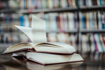 Open book with books piled up on the table in the library. Basic education concept.