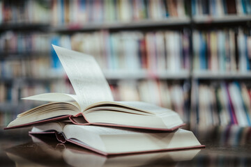 Open book with books piled up on the table in the library. Basic education concept.