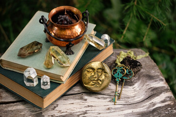 witch copper cauldron, crystal minerals, symbolic moon amulet, vintage keys, spell books close up in forest. Magic Ritual, witchcraft. spiritual esoteric practice.