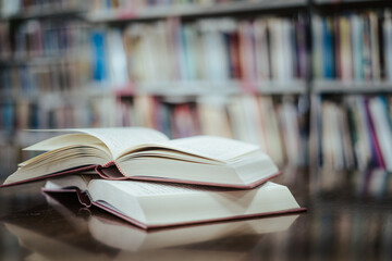 Open book with books piled up on the table in the library. Basic education concept.