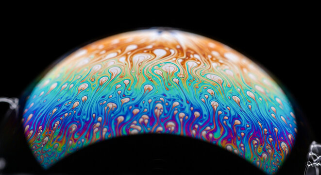 Macro view of a colorful soap bubble s surface displaying iridescent hues and tiny bubbles