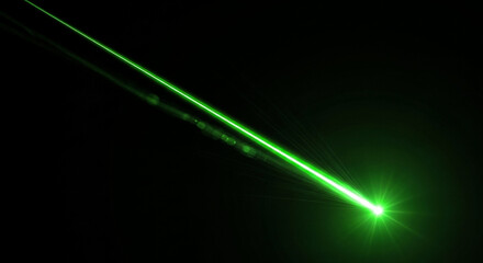 A single intense green laser beam cuts through the blackness originating from a bright concentrated point and extending diagonally upwards The light creates a visible glowing path