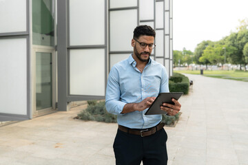 Male Business executive using a tablet outside of a modern office building
