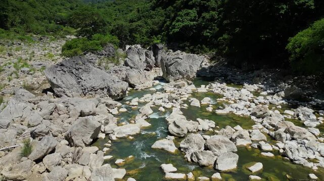 A smooth lateral drone shot glides sideways over Tinipak River, showcasing the stunning white rock formations and surrounding lush greenery in Tanay Rizal, Philippines.
