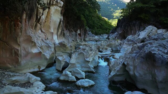 A wide drone shot moves forward, gradually closing in to highlight the flowing Tinipak River and stunning white rock formations in Tanay Rizal, Philippines.