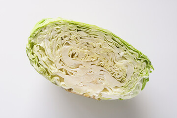 Obraz premium Top view of a cross-section of a green cabbage, showcasing detailed leaf layers and natural structure, placed on a white background.