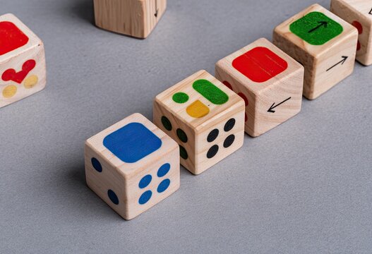 Wooden dice with various colored shapes and symbols arranged on a gray surface
