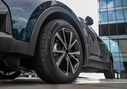 wheels with tires and aluminium rims. Parked  car model, in gray metallic color, with 1.8-liter hybrid engine Low angle view