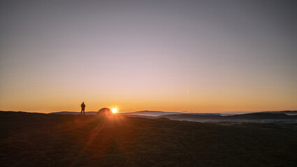 An explorer and his wild camping tent on a hill in England at sunrise © UAV4