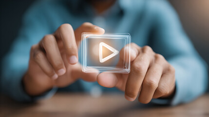 A person’s hands are holding a glowing, digital play button, symbolizing the start of a video or project.