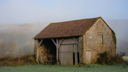 Obraz premium Old Stone Barn in the Misty Countryside on an Autumn Morning