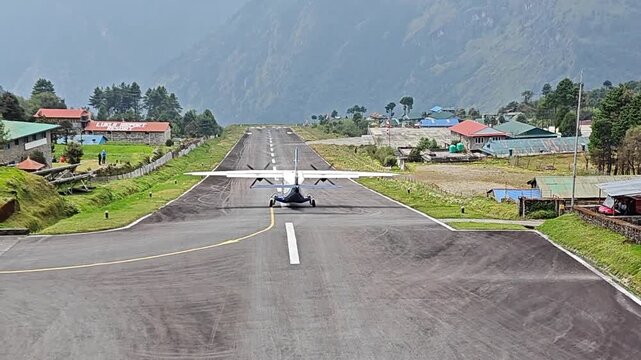 Lukla, Nepal - May 08, 2025: Lukla airport. Small airplane ascends from picturesque runway surrounded by mountains and village