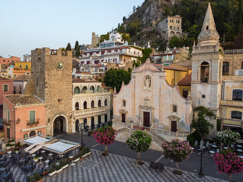 Aerial view of the Piazza IX Aprile, with its ancient clock tower and the baroque Church of Saint Joseph, bathed in the warm Sicilian sun, Taormina, Sicilia, Italy.