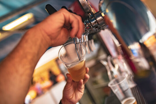 Bartender pouring craft beer into plastic cup at festival