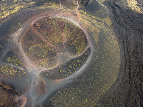 Aerial view of the volcanic landscape's dark, textured slopes and the Rifugio Sapienza trails, contrasting with the crater's lighter tones, Piazzale Rifugio Sapienza, Sicilia, Italy.