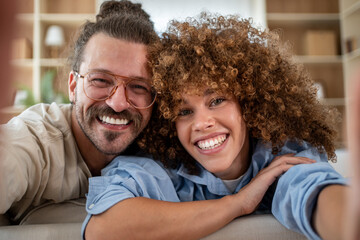 Fototapeta premium Happy couple taking selfie on sofa at home