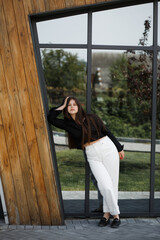 Girl in white pants and black blouse near mirror wall