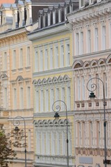 A row of building facades in pastel colors stands side by side he architecture features neoclassical or Art Nouveau elements