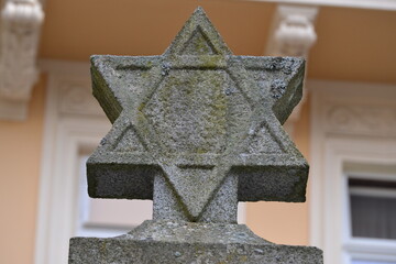 a weathered stone Star of David, likely from a historical monument or a Jewish cemetery. 