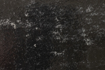 Black glossy surface with scratches, abrasions and white inclusions for backgrounds and design