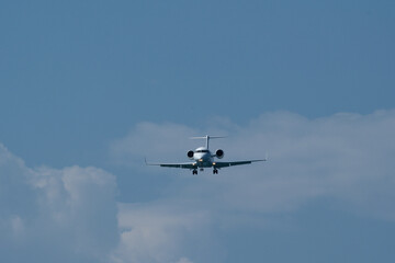 Airplane in the blue sky with white clouds and landing gear. The private plane is preparing to land at the airport on a sunny day.