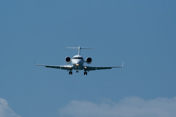 Airplane in the blue sky with white clouds and landing gear. The private plane is preparing to land at the airport on a sunny day.