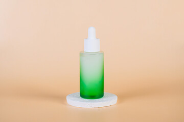 Green glass cosmetic bottle, Skin care or sunscreen cosmetic with stylish props on cream background.