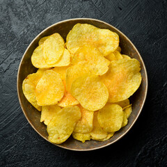 Beer snacks. Ceramic bowl with potato chips. Top view, on a stone background.