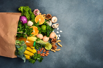 Healthy food background. Healthy food in paper bag vegetables and fruits on gray stone background....
