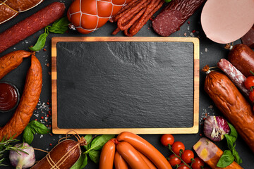 Assortment of sausages and salami on a table with a cutting board. Top view. Free space for text or...