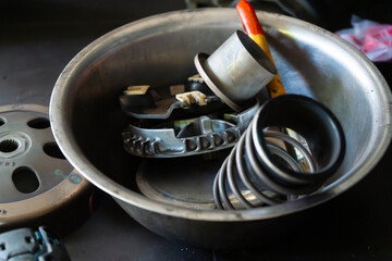 Detailed close-up of a mechanic’s hand performing maintenance on a scooter motorcycle’s CVT (Continuously Variable Transmission) system in a professional workshop. Ideal for illustrating concepts.