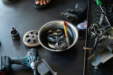 Detailed close-up of a mechanic’s hand performing maintenance on a scooter motorcycle’s CVT (Continuously Variable Transmission) system in a professional workshop. Ideal for illustrating concepts.