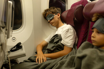 Teenage child, boy, sleeping on board of aircraft, traveling on vacation with parent and siblings...