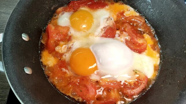 Eggs are fried in a pan with vegetables. Shakshuka