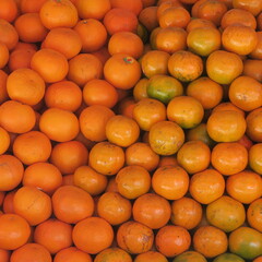 many small oranges in a pile, at a market stall in Asia