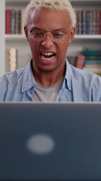 Frustrated African American man sits at his computer, waving his hands in exasperation, clearly annoyed by his team work or the challenges of working on the computer.