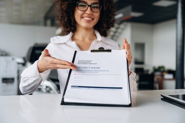 Fulfill the document of buying. Female employee is in the car retail shop